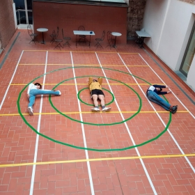 imatge d'un pati on tres persones estirades al terra formen la paraula PIC